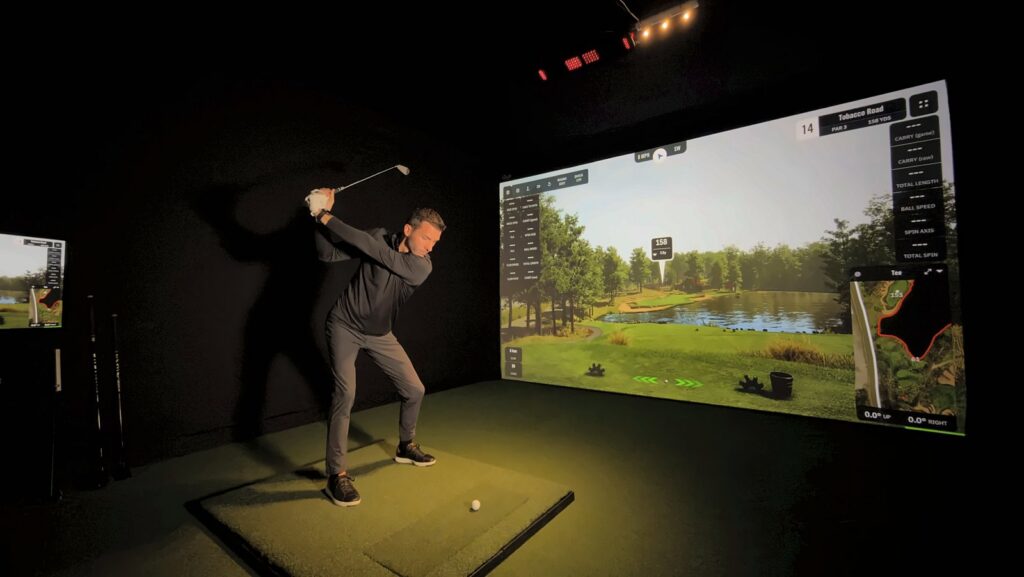Jay at the top of his backswing in a Carl's Place PRO enclosure with a ProTee VX on the ceiling and GSPro on the screen