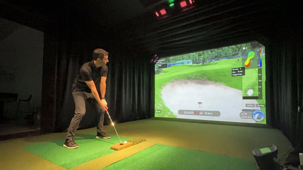 Jay hitting a bunker shot off an Uneekor trouble mat insert under the EYE XO2 in the GSV basement studio